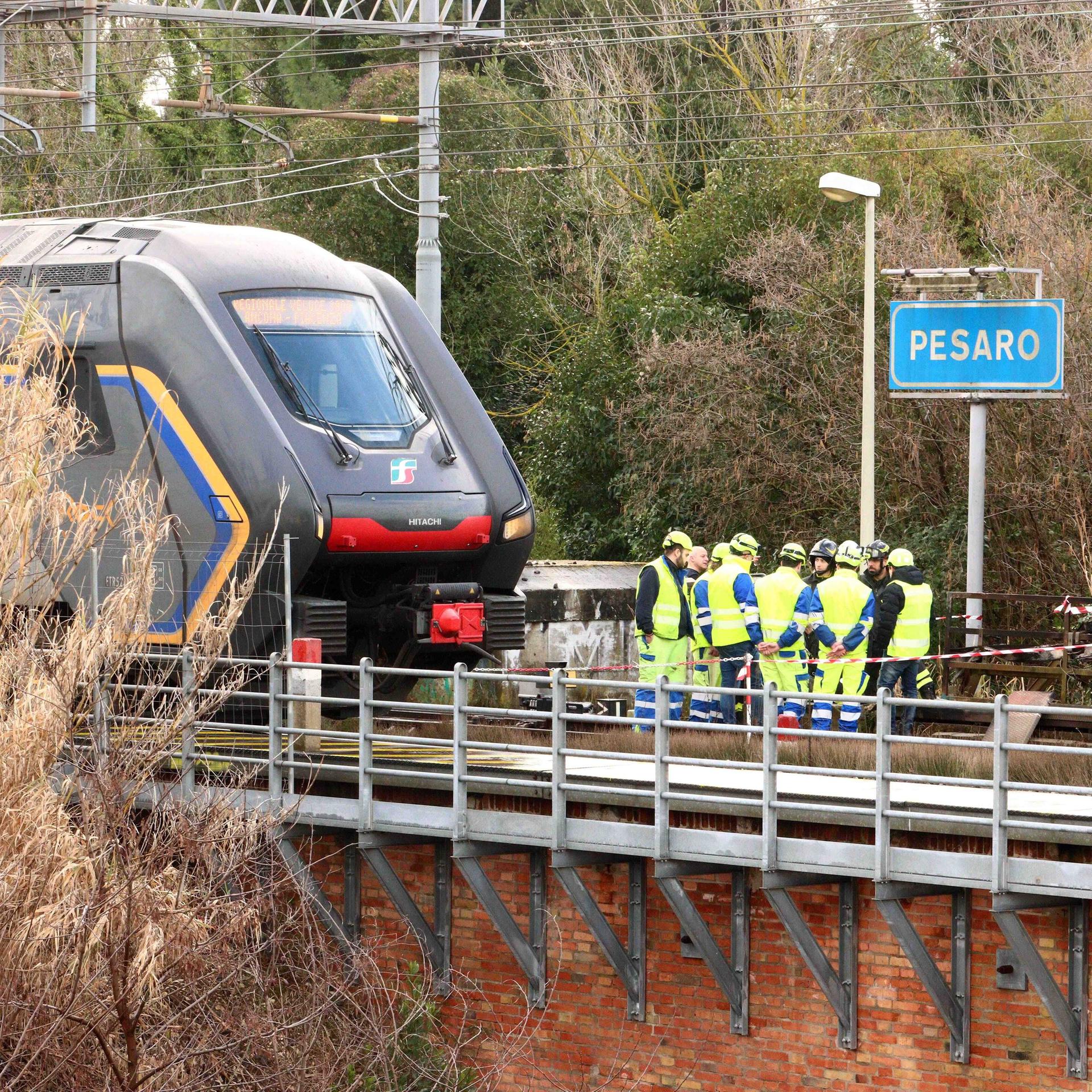 Einsatzkräfte stehen neben einer Bahn auf der Strecke zwischen Bologna und Ancona. 
