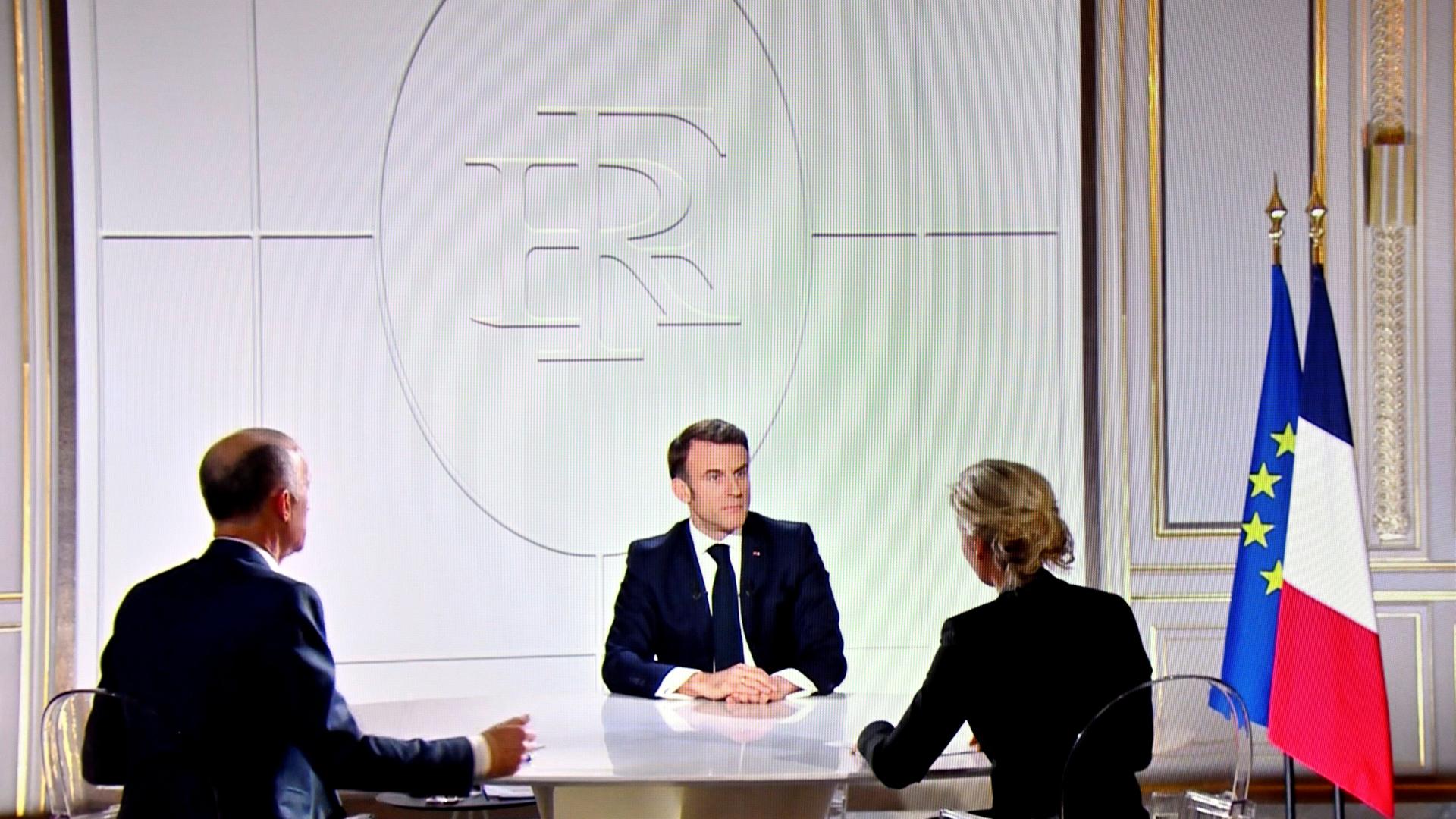 Der französische Präsident Macron in einem TV-Interview. Vor ihm sitzen zwei Journalisten.