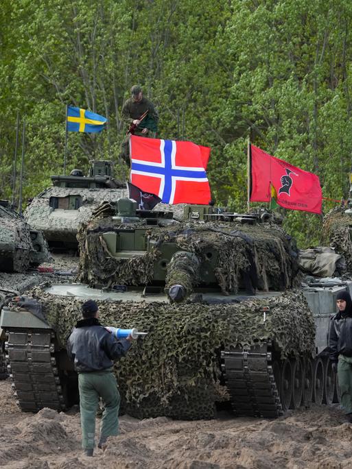 Panzer mit schwedischen, norwegischen und italienischen Flaggen bei einer Übung in einem Waldgebiet.