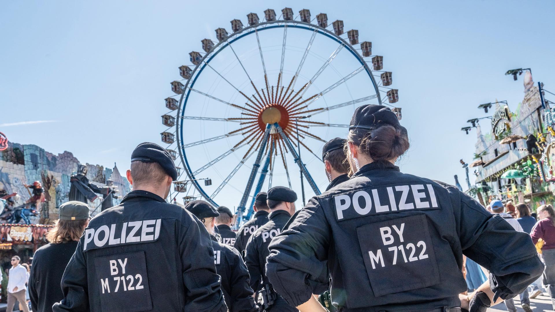 Eine Polizeistreife bewegt sich vor dem Riesenrad auf dem Oktoberfest 2024.