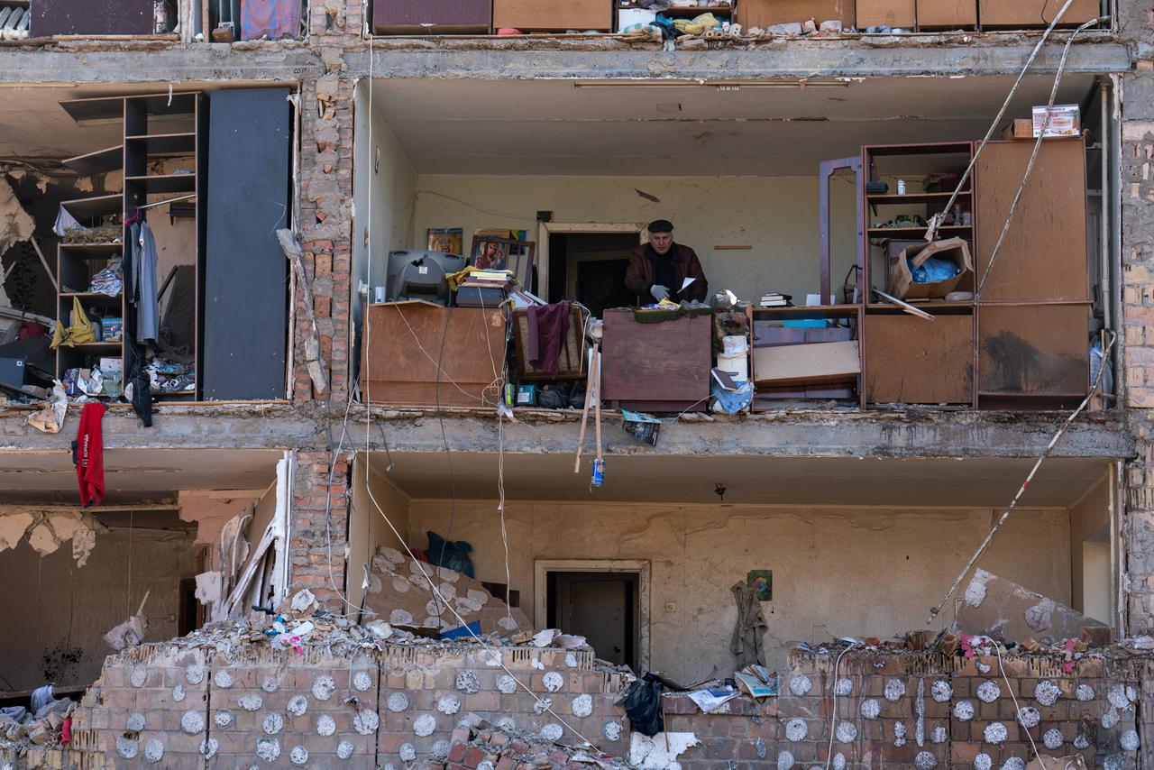 Die Wand eines Wohnhauses in Kiew ist nach einen Raketenangriff wegggerissen.  Der fast 70-jährige Pavil wirft Trümmer aus seinem Wohnhaus im zweiten Stock.