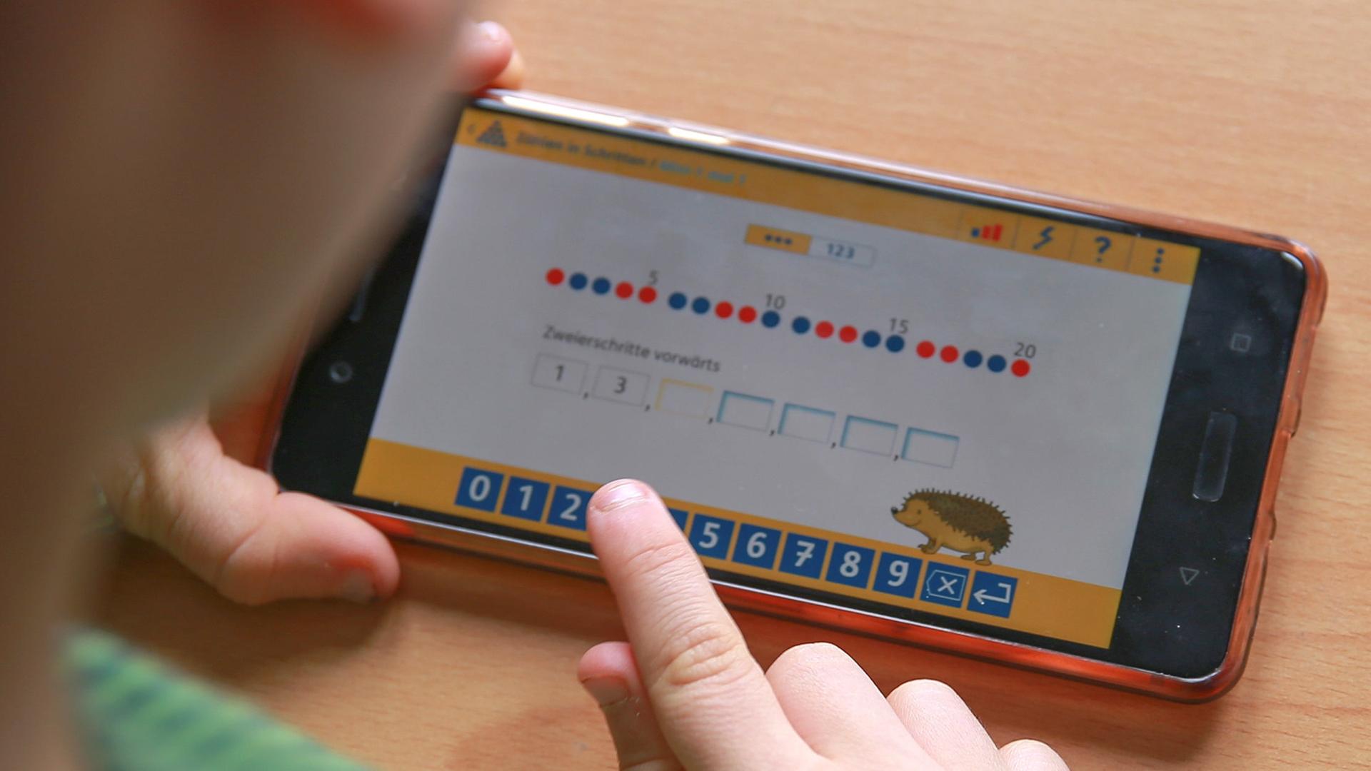  Ein Junge übt das Rechnen mit Hilfe einer App auf dem Smartphone.