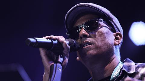 Der Sänger Xavier Naidoo singt mit dunkler Sonnenbrille im Gesicht live beim Giessener Kultursommer 2019 in ein Mikrofon.