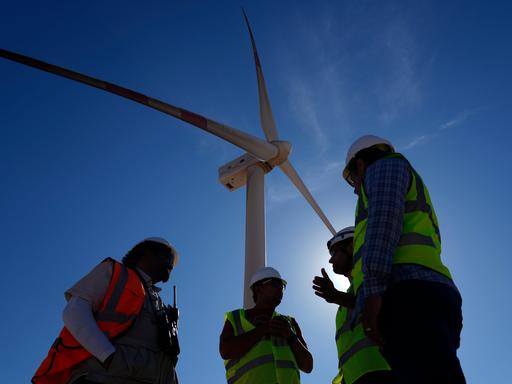 Ingenieure im Gespräch neben einer Windturbine in der Lekela Windenergie Station, in der Nähe von Ras Ghareb, etwa 300 Kilometer von Kairo entfernt