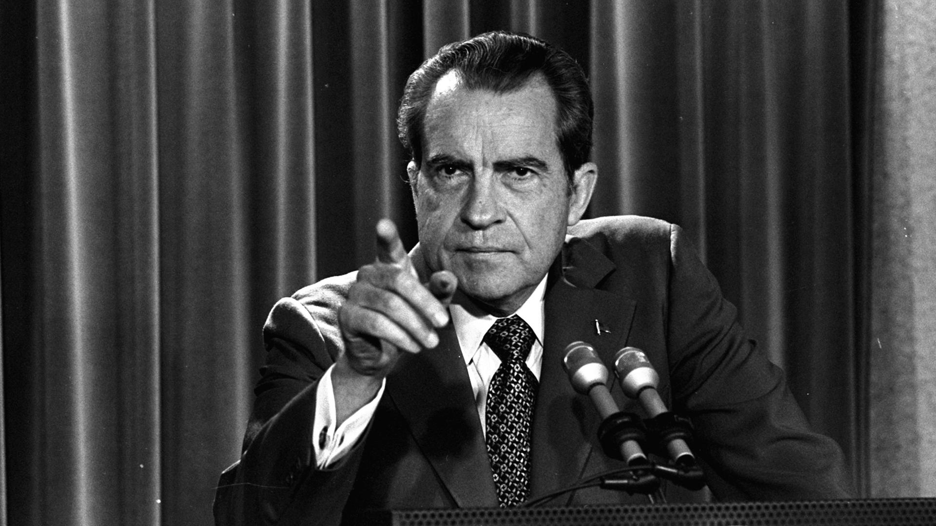 Schwarzweißaufnahme von Präsident Nixon an einem Rednerpult, der mit dem Finger Richtung Publikum zeigt.