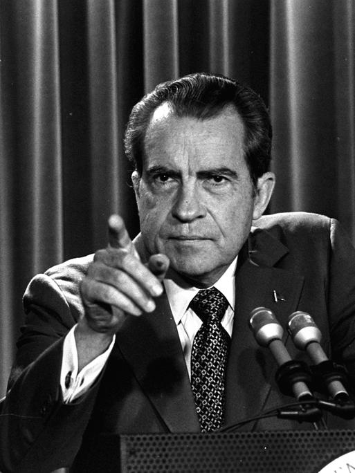 Schwarzweißaufnahme von Präsident Nixon an einem Rednerpult, der mit dem Finger Richtung Publikum zeigt.
