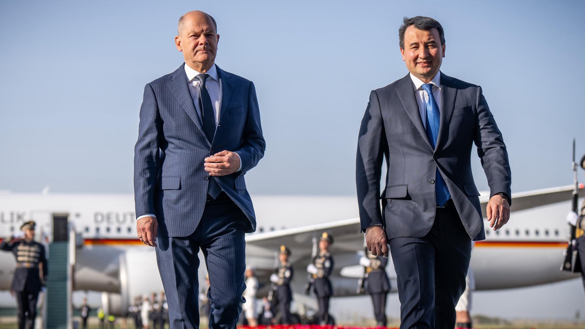 Bundeskanzler Olaf Scholz (l, SPD), wird am Flughafen von Abdulla Aripow, Ministerpräsident von Usbekistan, begrüßt. 