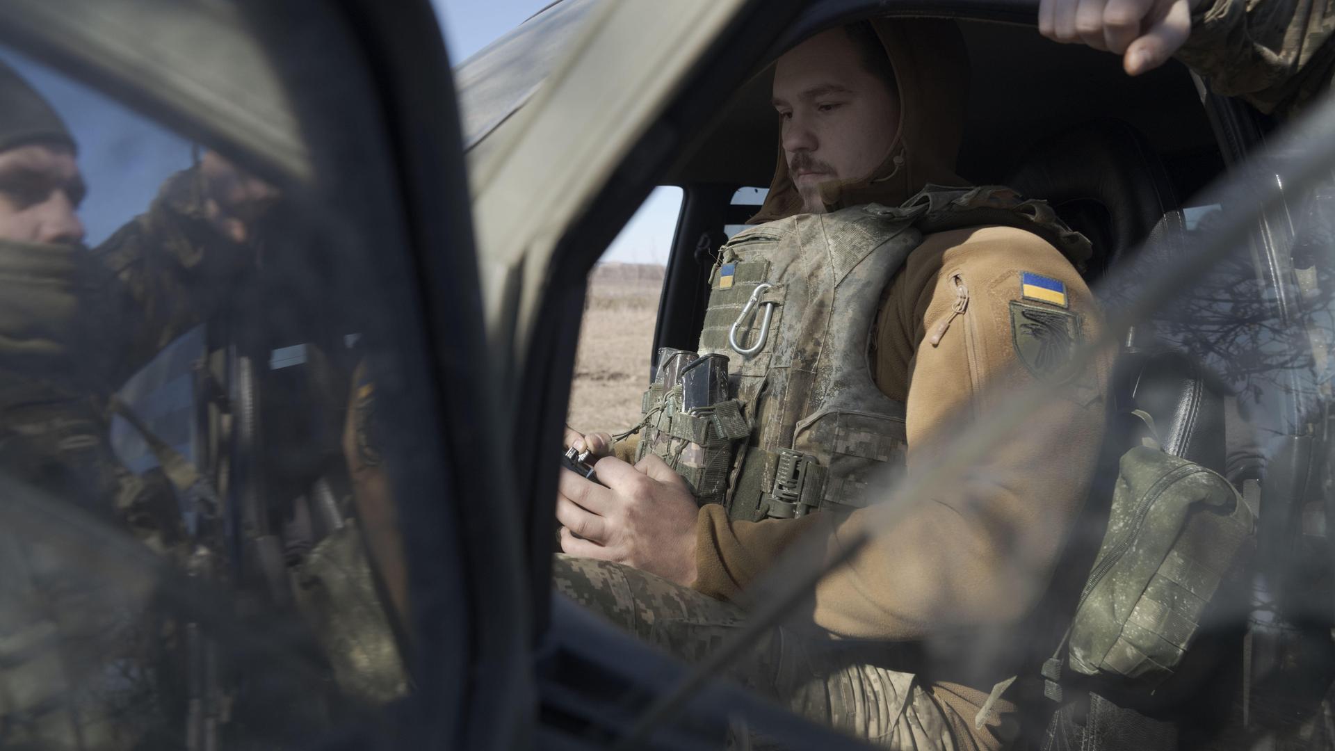 Ein ukrainischer Soldat steuert eine Drohne in Donezk. Er sitzt in Uniform in einem Fahrzeug.