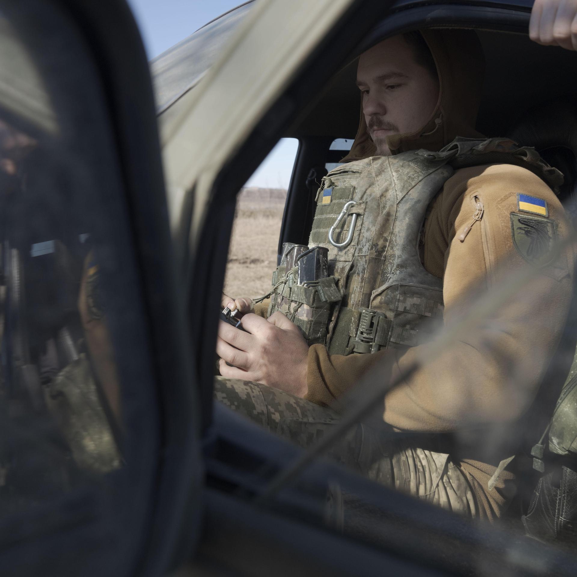 Ein ukrainischer Soldat steuert eine Drohne in Donezk. Er sitzt in Uniform in einem Fahrzeug.