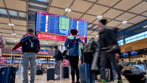 Fluggäste informieren sich an den Abflugtafeln im Terminal 1 des Flughafens Berlin Brandenburg. 