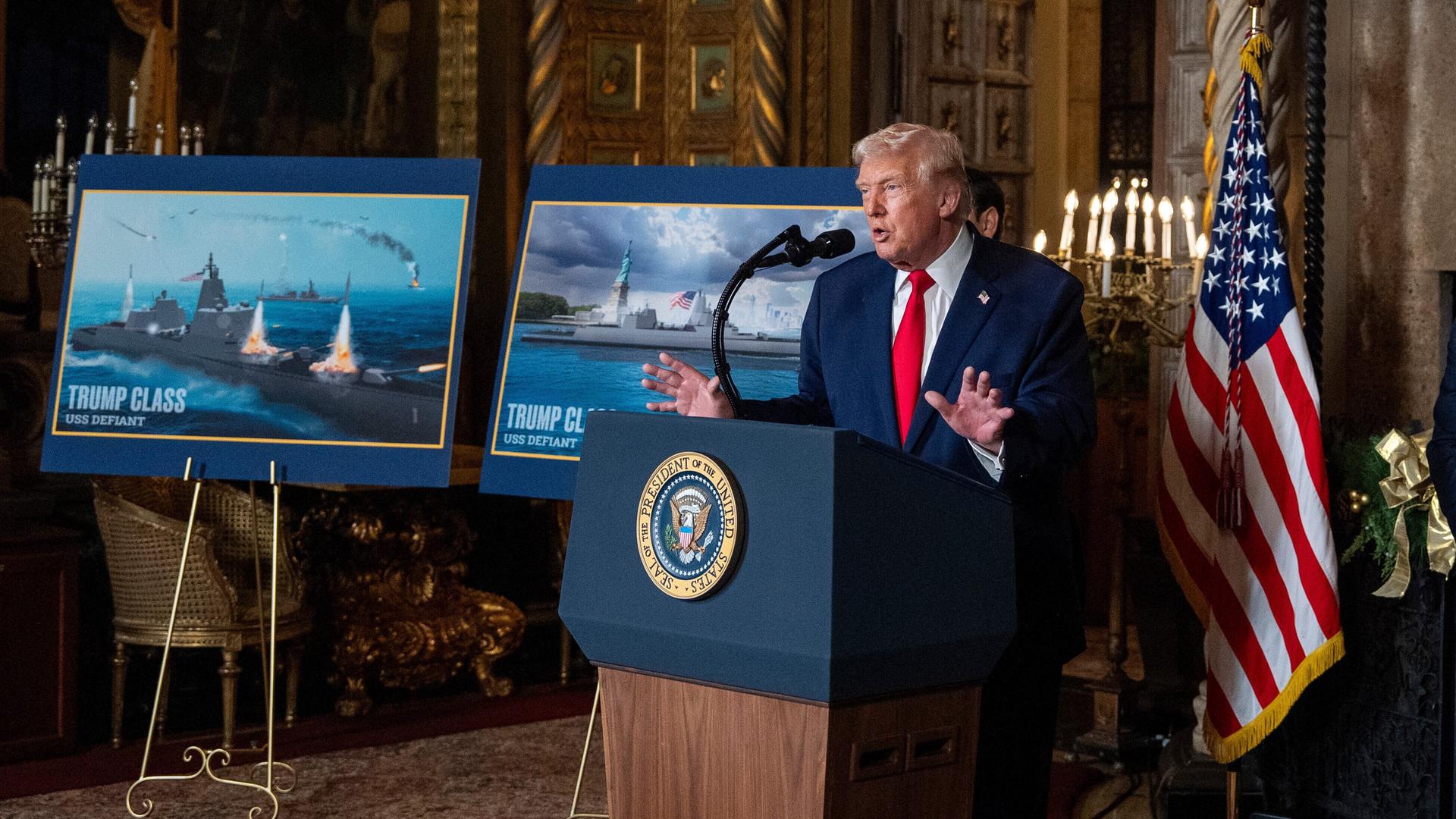 Donald Trump an einem Rednerpult, daneben Bilder von geplanten Schlachtschiffen, die nach ihm benannt werden sollen. Donald Trump an einem Rednerpult, daneben Bilder von geplanten Schlachtschiffen, die nach ihm benannt werden sollen.