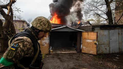 Ein ukrainischer Soldat geht nach dem Einschlag einer russischen Rakete in Charkiw an einer brennenden Garage vorbei.