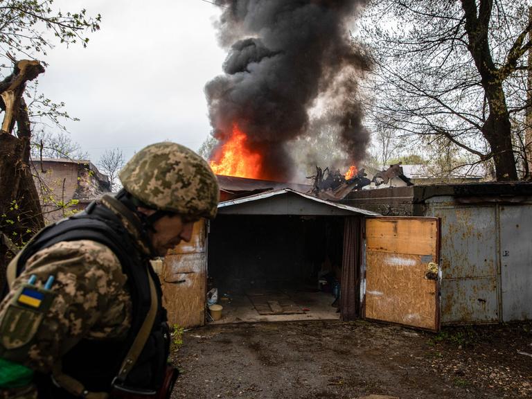 Ein ukrainischer Soldat geht nach dem Einschlag einer russischen Rakete in Charkiw an einer brennenden Garage vorbei.
