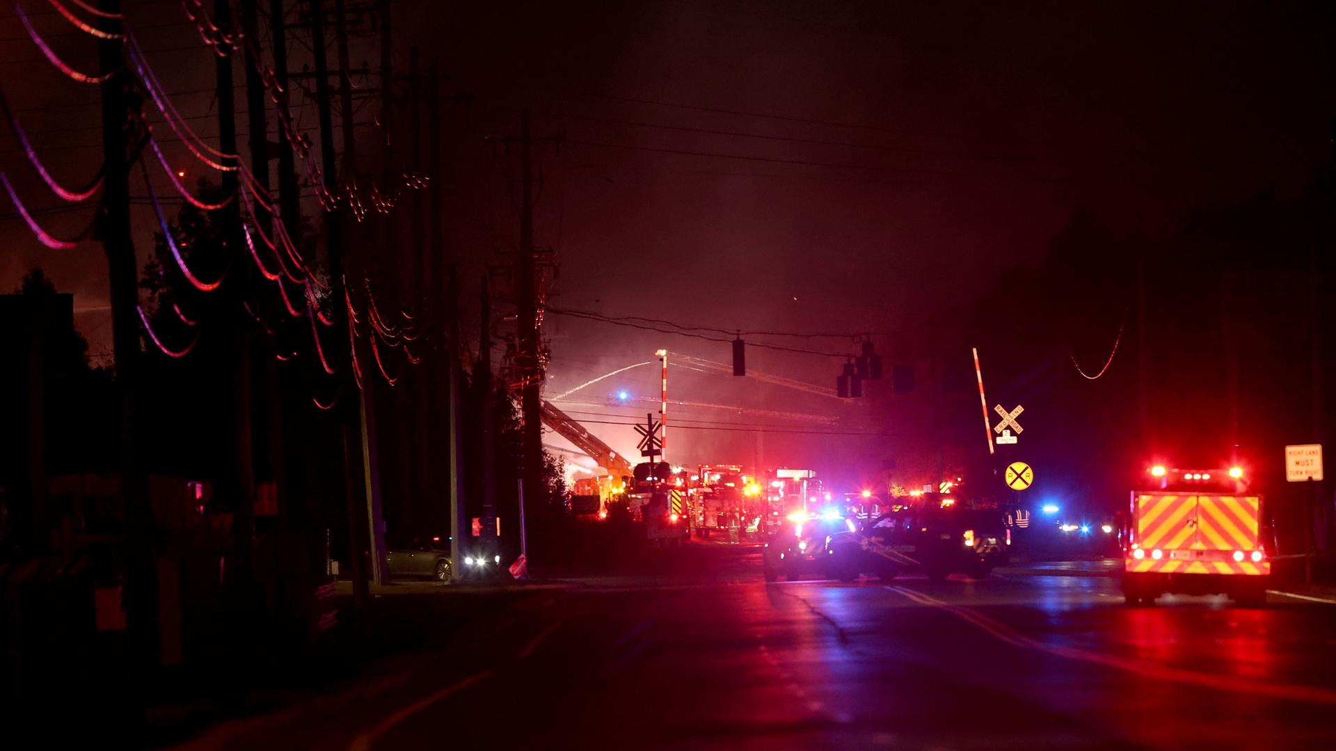 Feuerwehrautos mit Warnlichtern sind in der Nacht auf einer Straße. 