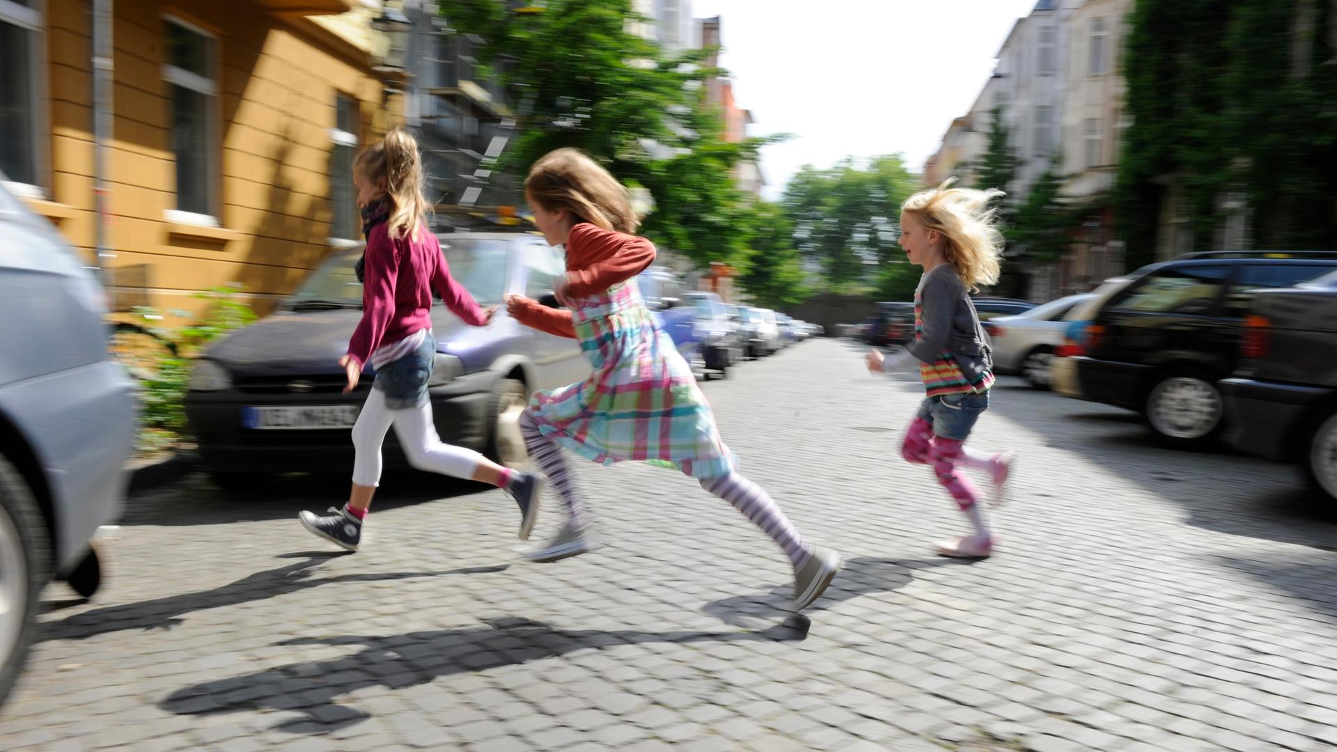 Drei Mädchen rennen über eine Straße in Düsseldorf, Nordrhein-Westfalen Drei Mädchen rennen über eine Straße in Düsseldorf, Nordrhein-Westfalen