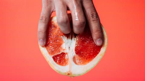 Zwei Finger in einer Grapefruit