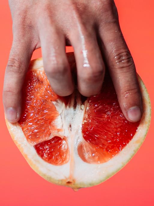 Zwei Finger in einer Grapefruit