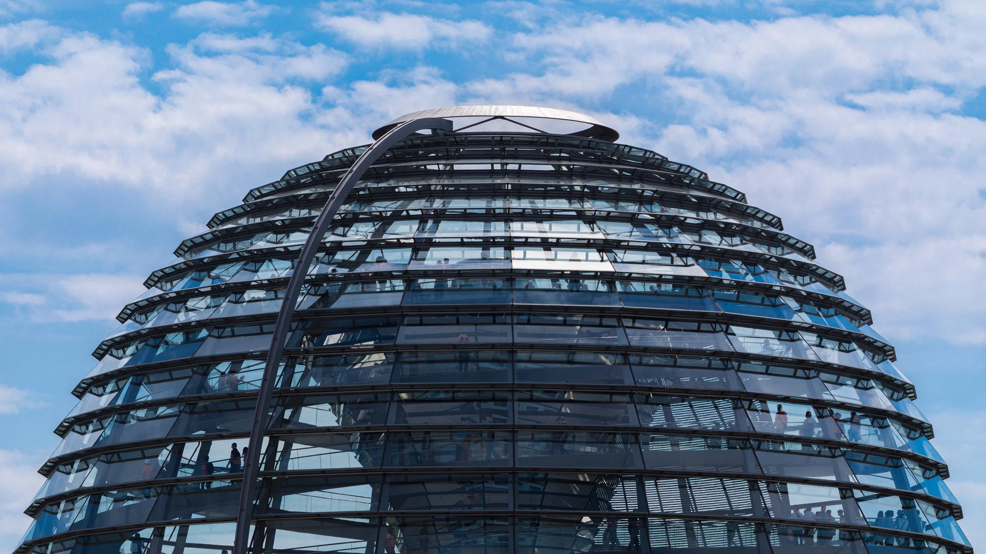 Die Glas-Kuppel auf dem Gebäude des deutschen Bundestages vor leicht bewölktem Himmel.