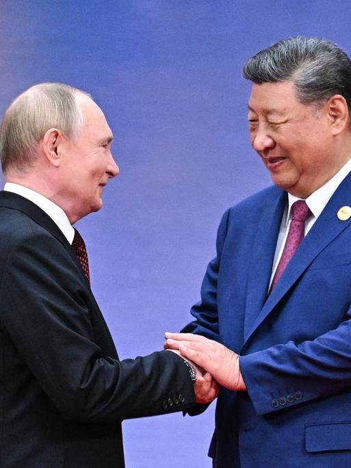 Xi Jinping schüttelt Putin bei einem Empfang die Hände
