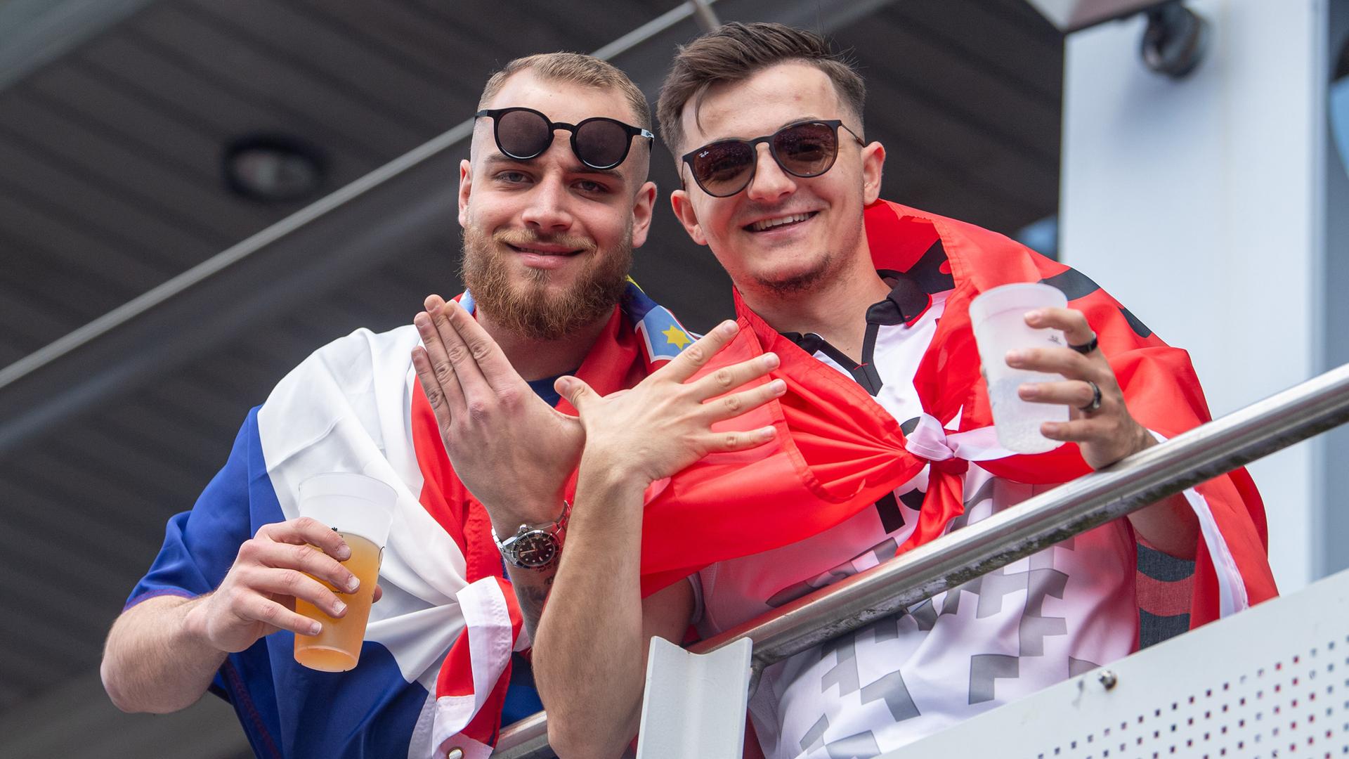 Ein Mann mit umgehängter kroatischer Flagge und ein Mann mit albanischer Flagge um die Schultern formen mit je einer Hand zusammen das umstrittene Doppeladler-Symbol Ein Mann mit umgehängter kroatischer Flagge und ein Mann mit albanischer Flagge um die Schultern formen mit je einer Hand zusammen das umstrittene Doppeladler-Symbol