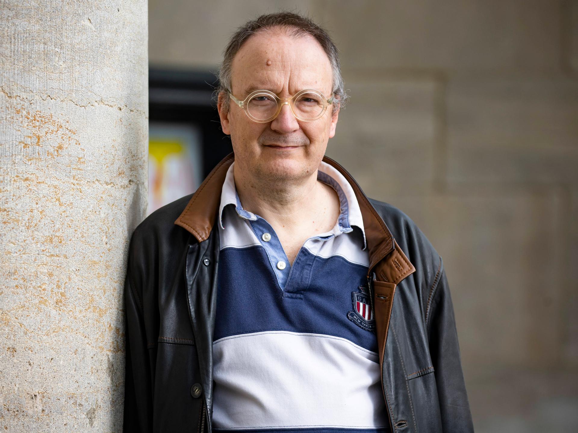 Thomas Brussig posiert in Polohemd und Nappalederjacke im Freien für ein Porträt.