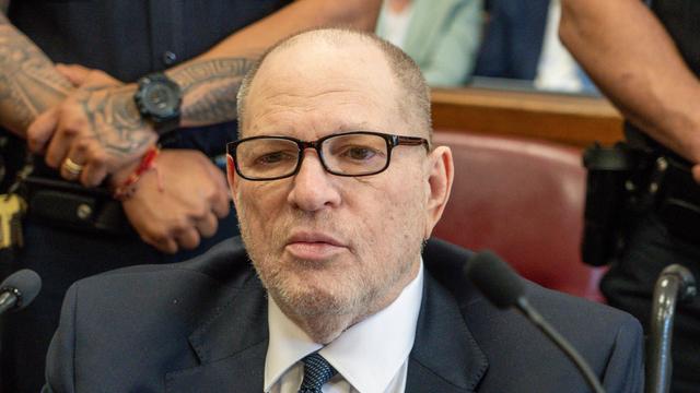 Harvey Weinstein sitzt in einem Gerichts-Saal. Er trägt einen dunklen Anzug und eine Brille. 
