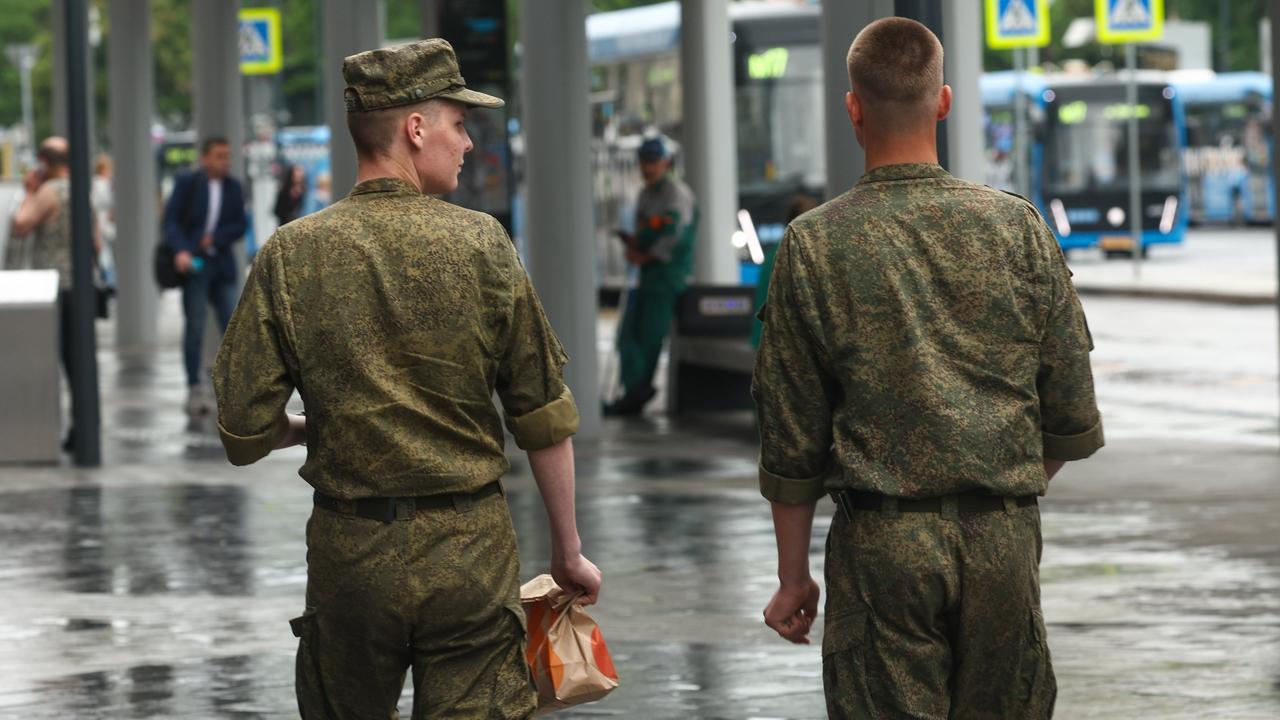 Zwei russische Soldaten schlendern über eine Straße in Moskau. Ansicht von hinten. Zwei russische Soldaten schlendern über eine Straße in Moskau. Ansicht von hinten.