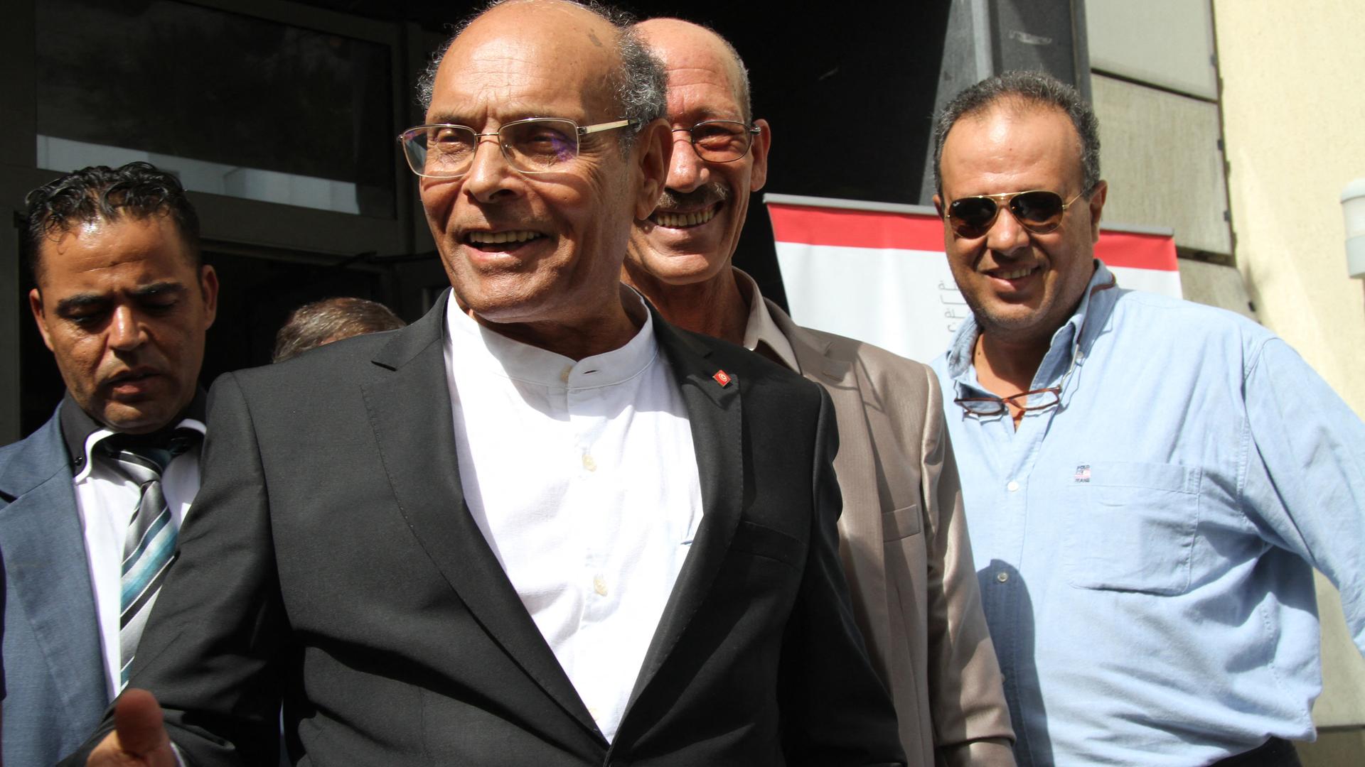 Der frühere tunesische Präsident Marzouki in schwarzem Jacket und weißem Hemd lächelt bei Sonnenschein seinen Gesprächspartner an. Der frühere tunesische Präsident Marzouki in schwarzem Jacket und weißem Hemd lächelt bei Sonnenschein seinen Gesprächspartner an.