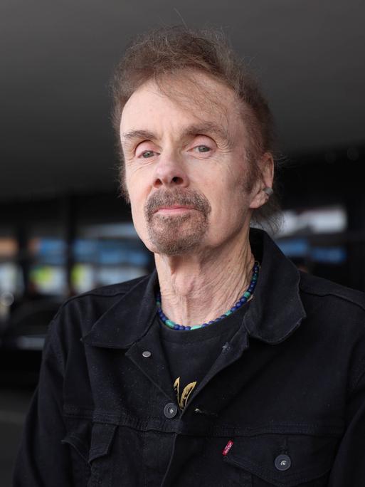 T.C. Boyle trägt eine schwarze Cordjacke, steht am Wiener Flughafen und schaut freundlich in die Kamera.