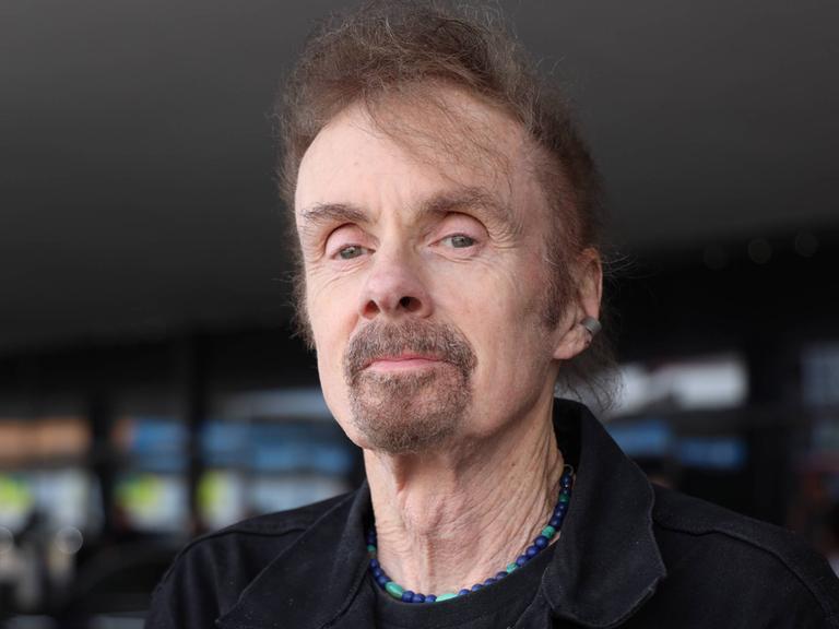 T.C. Boyle trägt eine schwarze Cordjacke, steht am Wiener Flughafen und schaut freundlich in die Kamera.