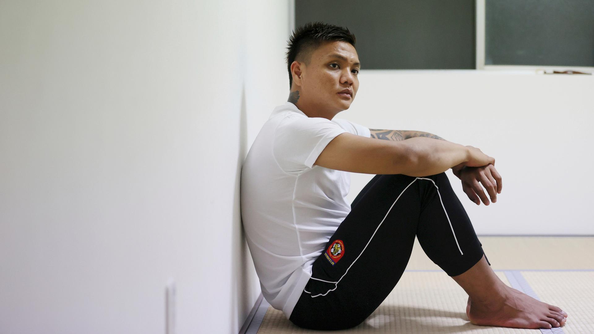 Der ehemalige Fußballnationaltorhüter Myanmars, Pyae Lyan Aung, sitzt am Boden und lehnt mit dem Rücken an der Wand ins seinem Apartment in Osaka. 