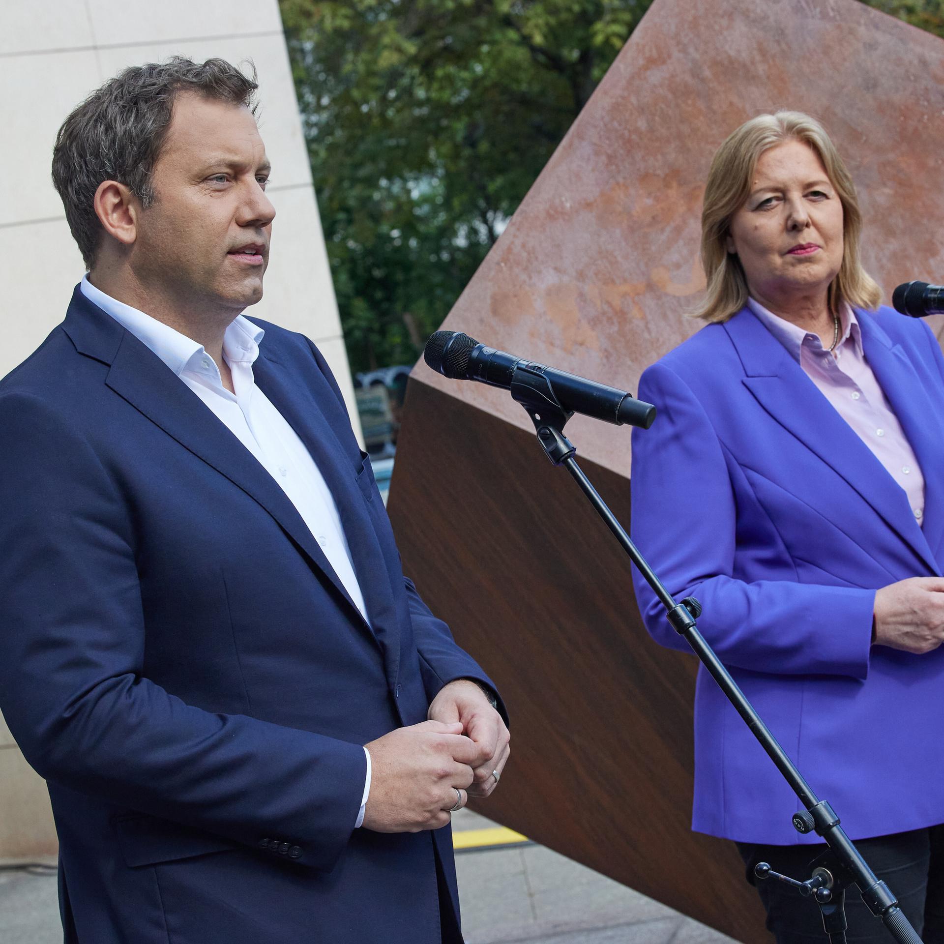 Die SPD-Vorsitzenden Klingbeil und Bas stehen vor dem Eingangsbereich des Willy-Brandt-Hauses in Berlin und sprechen in Mikrofone.