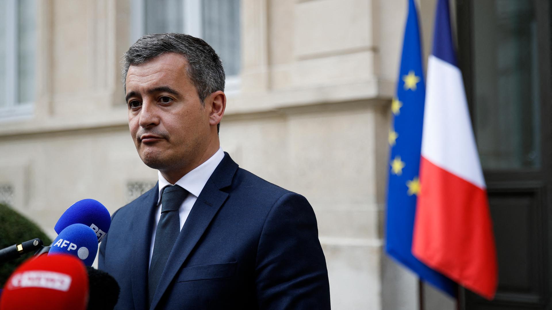 Frankreichs Innenminister Gerald Darmanin während einer Pressekonferenz vor dem Ministerium in Paris. Im Hintergrund die französische Nationalflagge und die EU-Flagge.