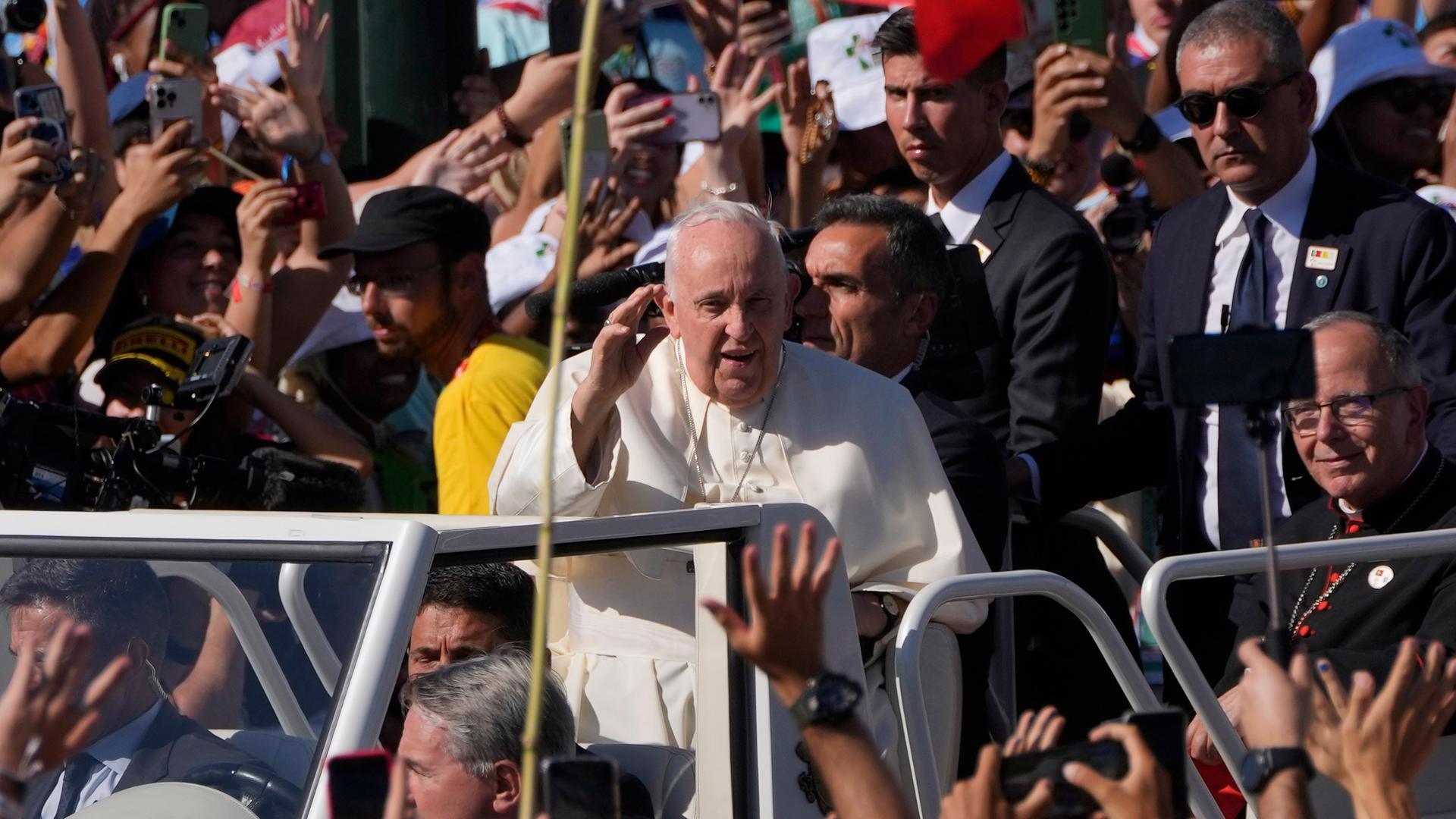 Der Papst fährt durch eine jubelnde Menge, um einen Kreuzweg mit jungen Menschen zu begehen. Er winkt in die Menge.