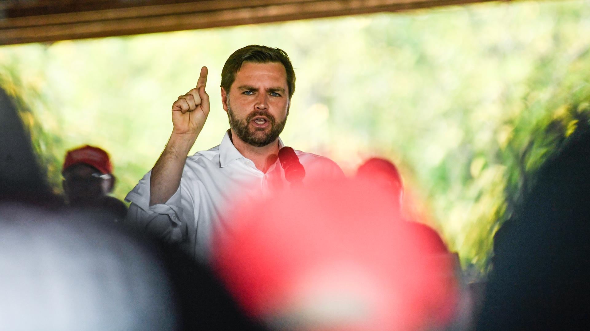 J. D. Vance steht in weißem Hemd mit einem Mikrofon in der Hand vor Publikum und spricht.