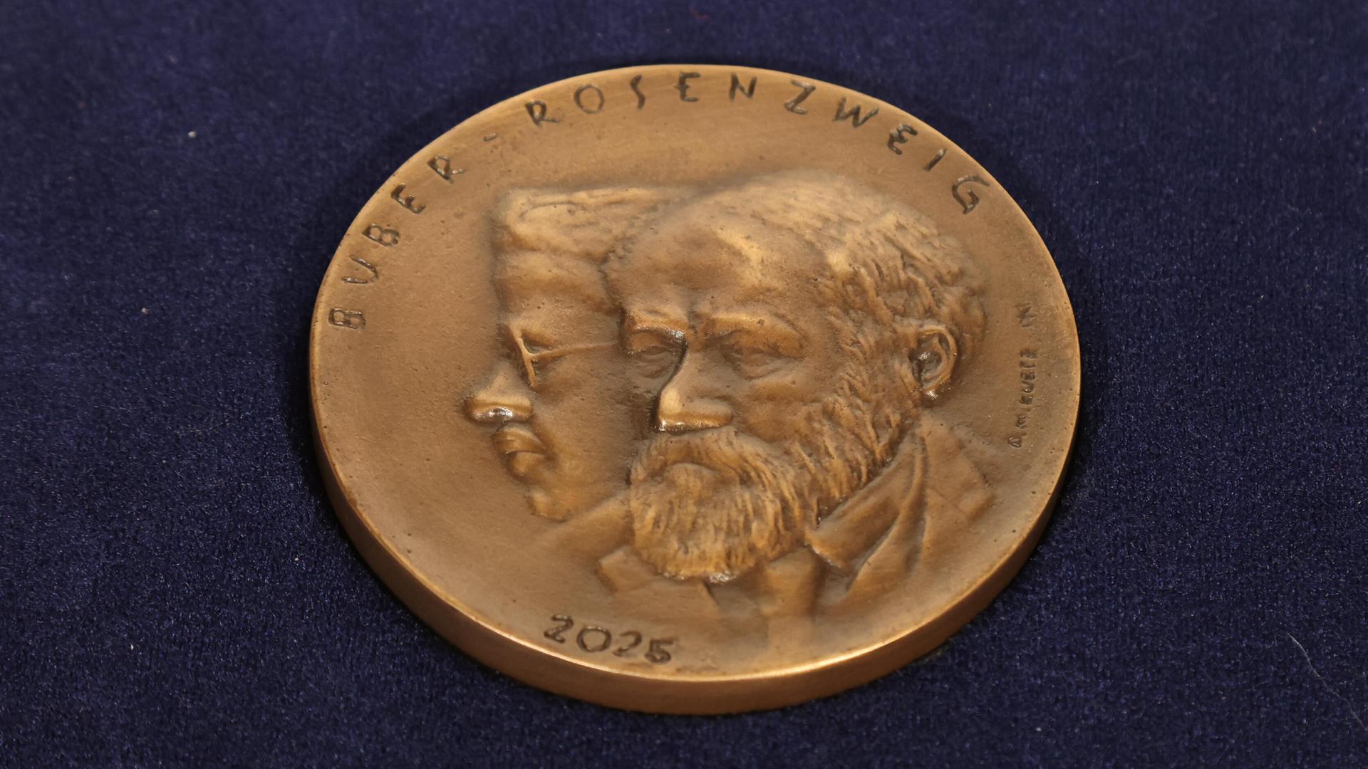 Foto der Buber-Rosenzweig-Medaille 2025 vor blauem Hintergrund. Foto der Buber-Rosenzweig-Medaille 2025 vor blauem Hintergrund.