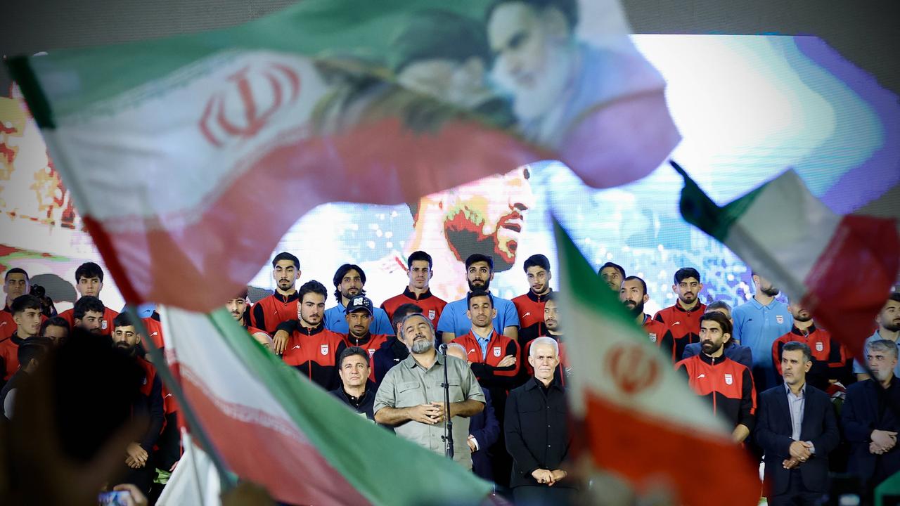 Veranstaltung der iranischen Fußballnationalmannschaft in Teheran vor der Weltmeisterschaft: Zu sehen sind Spieler, Cheftrainer und weitere Offizielle. Es werden Flaggen geschwungen. 
