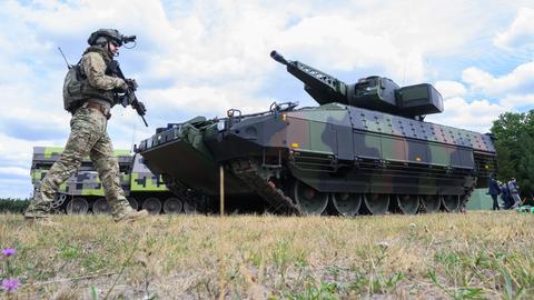 Ein "Infanterist der Zukunft" steht neben einem Schützenpanzer "Puma" des Rüstungskonzerns Rheinmetall 