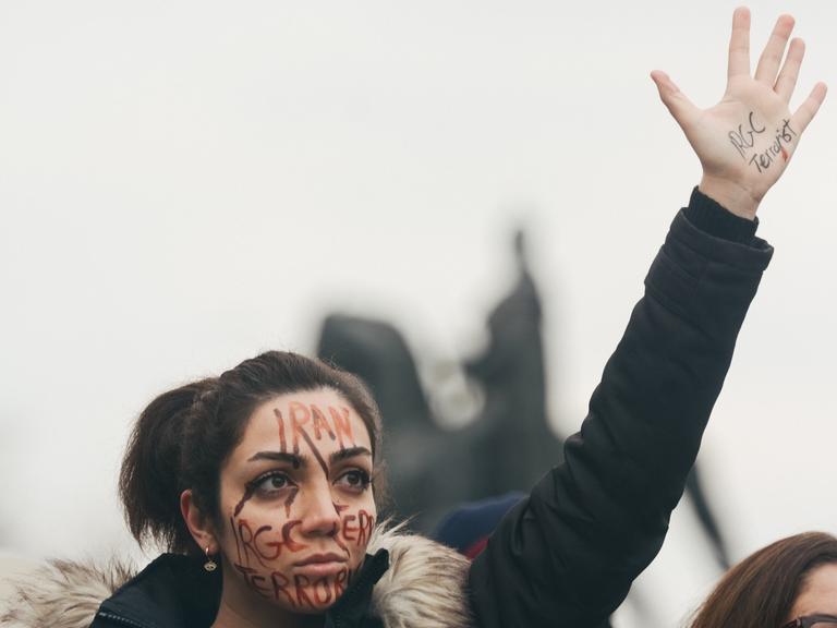 Eine Demonstrantin hält zum Protest gegen die Politik in Iran ihre Hand in die Höhe. 