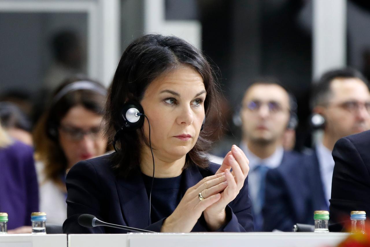 Die deutsche Außenministerin Baerbock sitzt mit Kopfhörer im nordmazedonischen Skopje einem Raum.