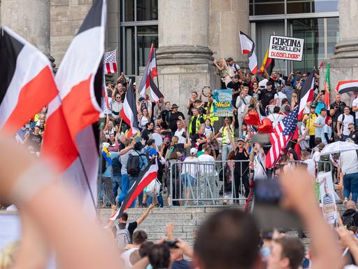 Mehrere hundert Menschen stehen mit Plakaten gegen die Corona-Maßnahmen sowie mit Reichsflaggen vor dem Berliner Reichstag. Das Foto ist im August 2020 entstanden.