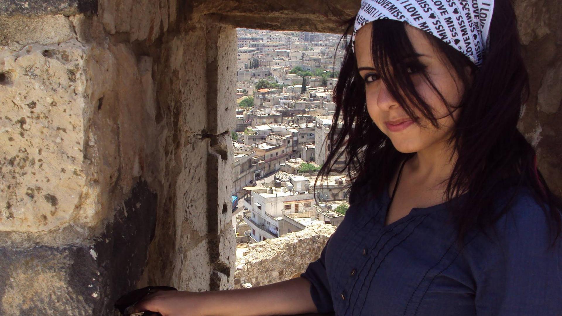 Hiba Obaid steht in der syrischen Stadt Masyaf und hinter ihr sieht man die historischen Gebäude der Stadt