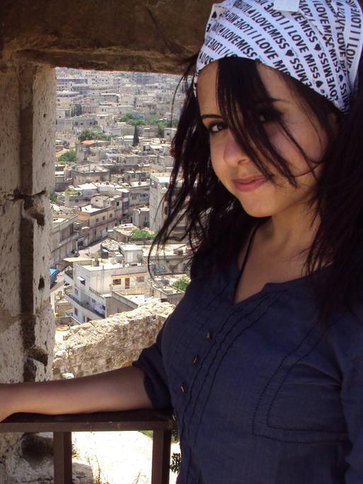 Hiba Obaid steht in der syrischen Stadt Masyaf und hinter ihr sieht man die historischen Gebäude der Stadt