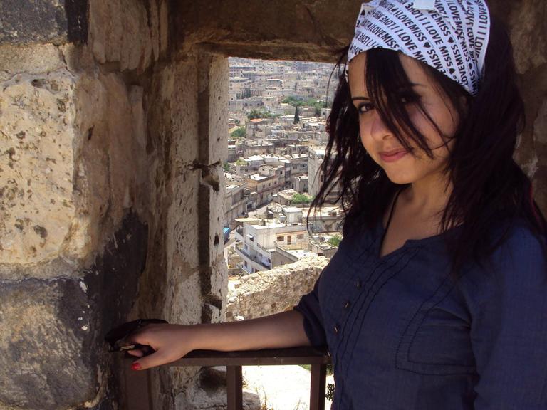 Hiba Obaid steht in der syrischen Stadt Masyaf und hinter ihr sieht man die historischen Gebäude der Stadt