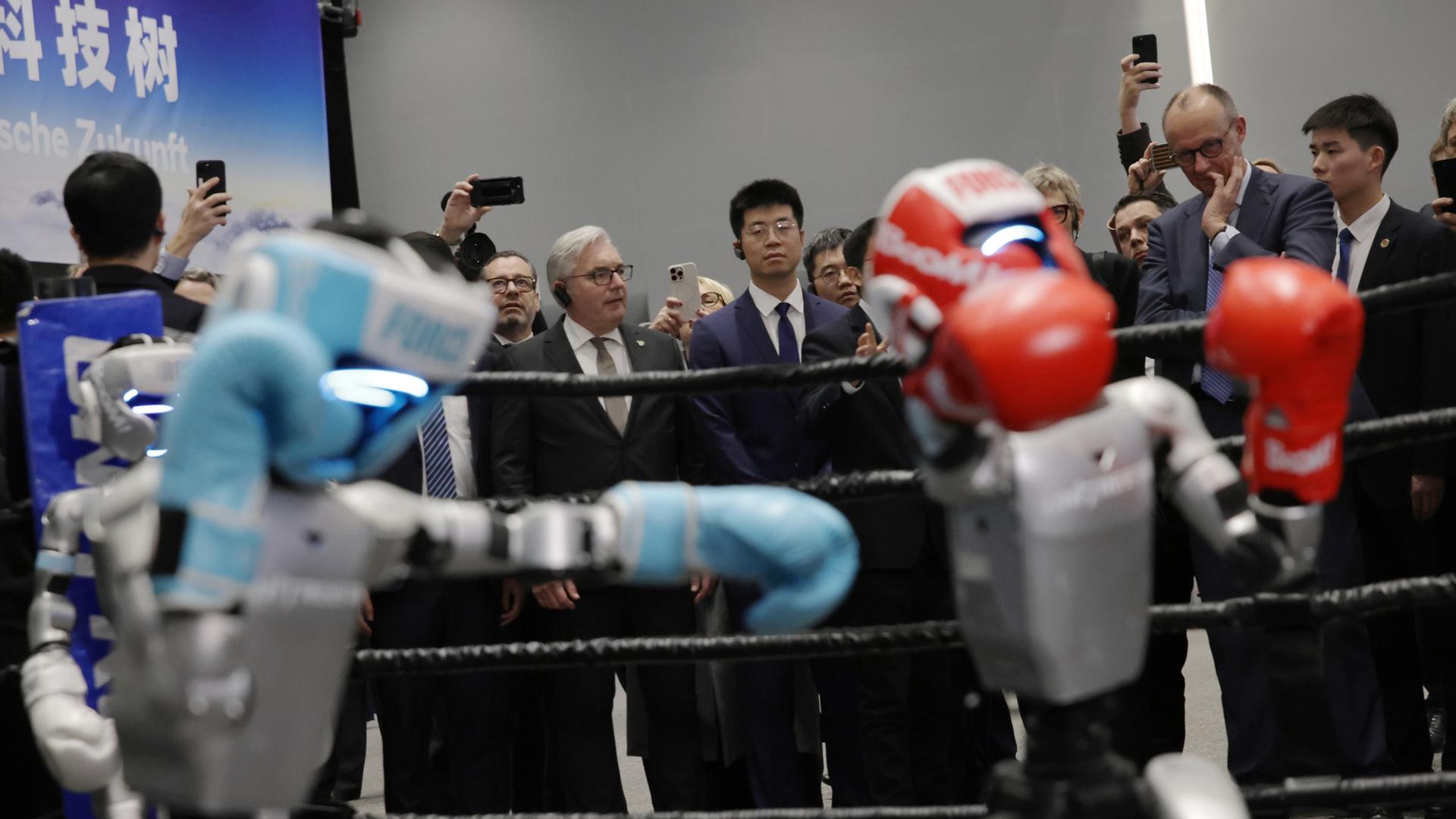 Bundeskanzler Merz beobachtet bei seinem offiziellen Besuch im Hauptsitz von Unitree Robotics in Hangzhou, China, einen humanoiden Roboter beim Boxen. Bundeskanzler Merz beobachtet bei seinem offiziellen Besuch im Hauptsitz von Unitree Robotics in Hangzhou, China, einen humanoiden Roboter beim Boxen.