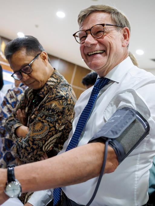 Bundesaußenminister Johann Wadephul (CDU) lässt sich den Puls messen und lacht dabei: Bei einem Besuch der staatlichen Fachhochschule für Gesundheitsberufe in Jakarta, Indonesien.