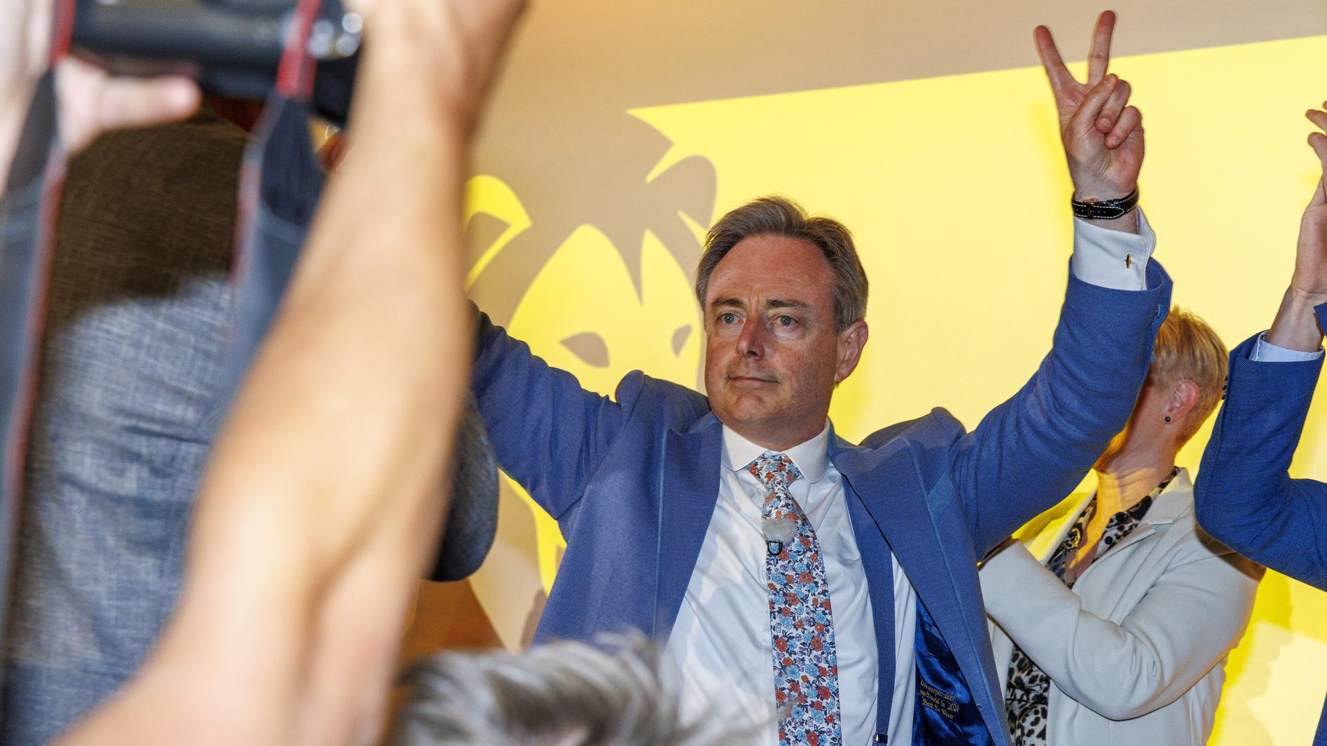 Der N-VA-Vorsitzende Bart De Wever macht vor dem Logo seiner Partei auf einer Wahlparty das Victory-Zeichen