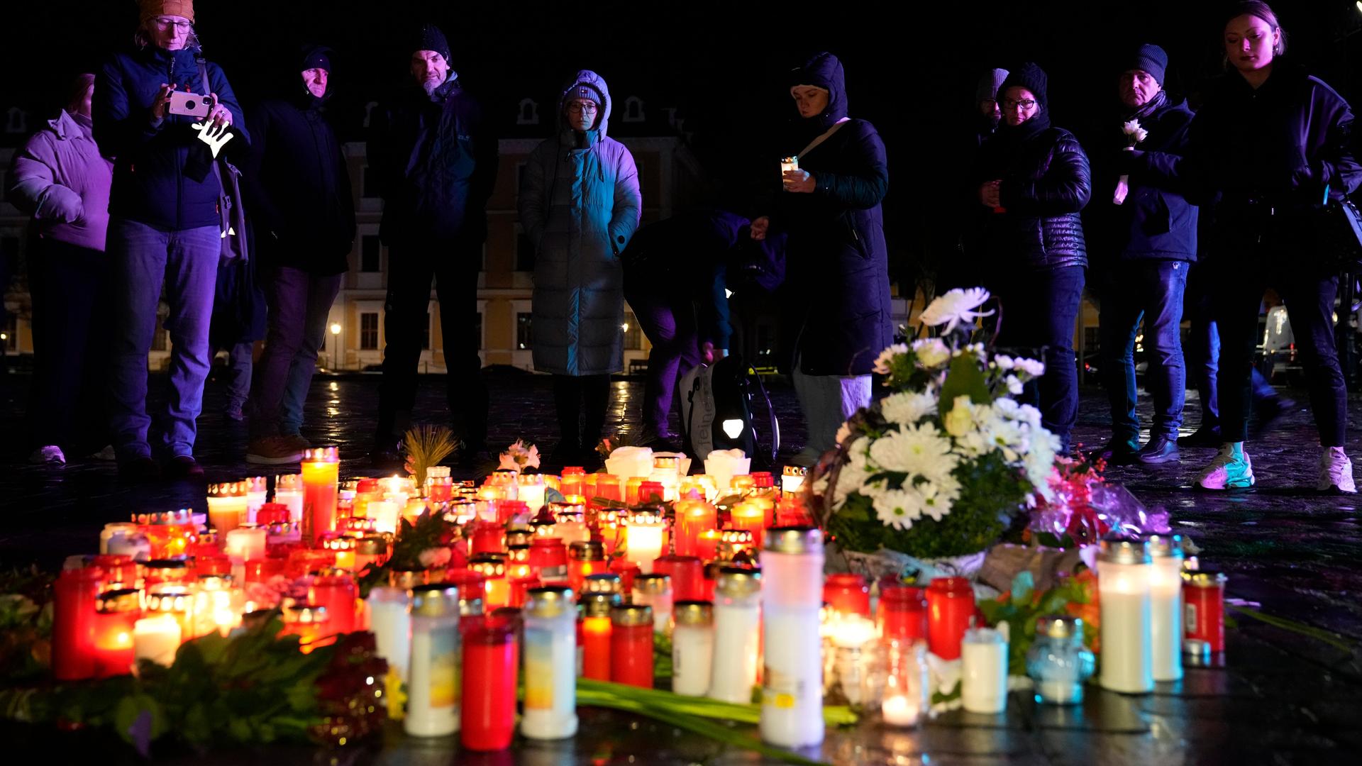 Menschen stehen hinter Kerzen und Blumen, die im Gedenken an die Opfer des Anschlags in Magdeburg vor dem Dom aufgestellt wurden.