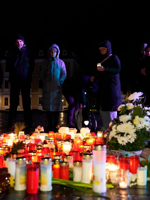 Menschen stehen hinter Kerzen und Blumen, die im Gedenken an die Opfer des Anschlags in Magdeburg vor dem Dom aufgestellt wurden.