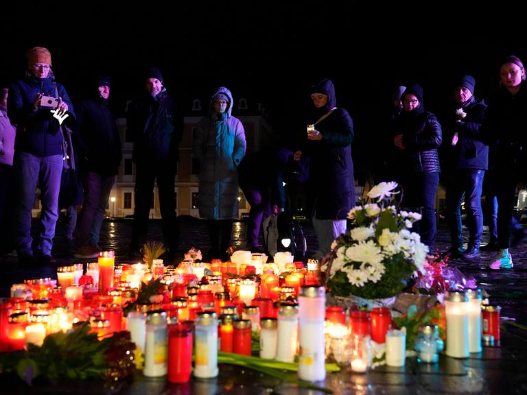 Menschen stehen hinter Kerzen und Blumen, die im Gedenken an die Opfer des Anschlags in Magdeburg vor dem Dom aufgestellt wurden.